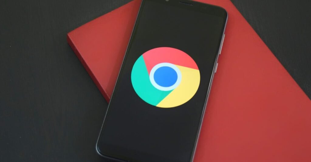 Close-up of a smartphone with Chrome browser logo on screen placed on a red notebook.