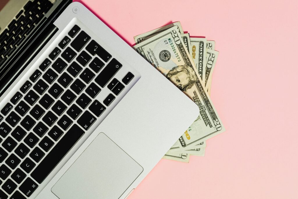 pexels photo 5706023 5706023 A laptop keyboard with dollar bills on a pink surface, symbolizing online business.
