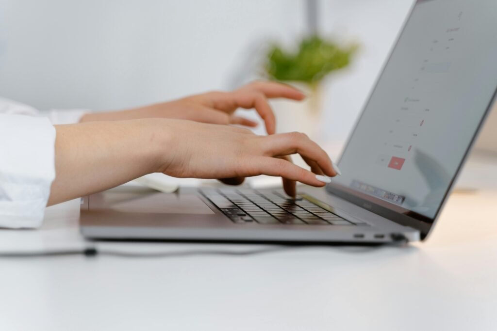 Hands typing on a laptop keyboard, ideal for concepts of remote work and technology.
